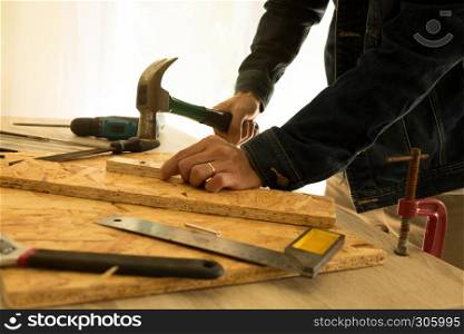 Close up of hammering a nail into wooden board
