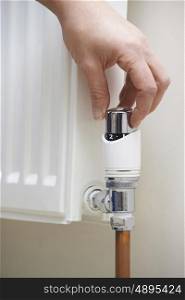 Close Up Of Hand Adjusting Heating Thermostat