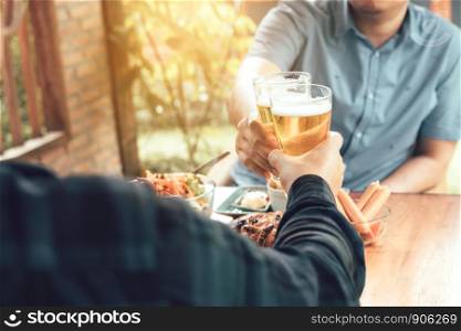 Close up of hand adult man holding beer glass and clinking together.