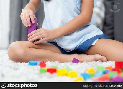 Close up of hand child playing with colorful plastic block at floor. Early learning developing to children with toys.