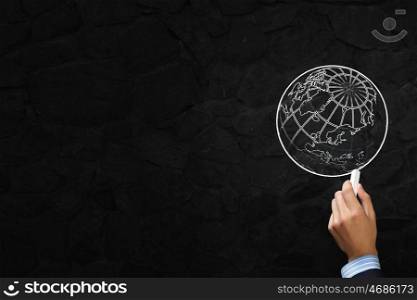 Close up of hand drawing globe on blackboard. Drawing globe