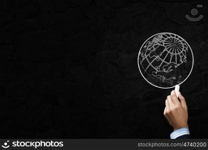 Close up of hand drawing globe on blackboard. Drawing globe