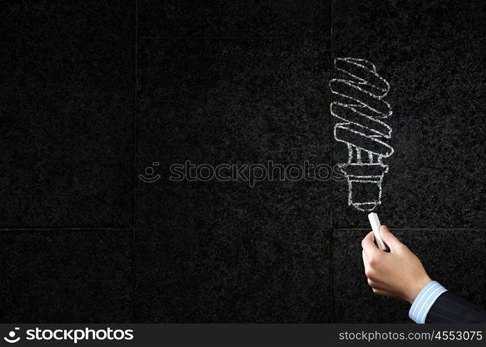 Close up of hand drawing light bulb with chalk. Light bulb