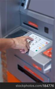 Close up of hand entering pin code at Automated Teller Machine, stock photo