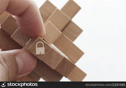 close up of hand holding padlock icon on cubic wood puzzle as internet security online business concept