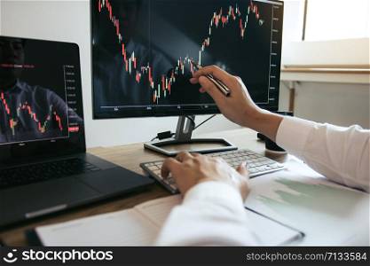 Close up of hand investors are pointing to laptop computer that have investment information stock markets and partners taking notes and analyzing performance data.