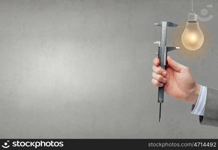 Close up of hand measuring light bulb with wrench. Measure it up