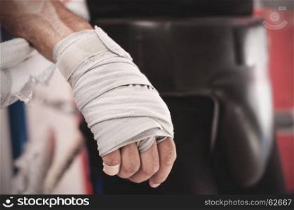 Close up of hand of boxer leaning on ropes on a boxing ring.