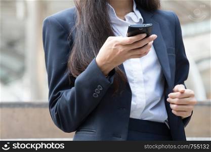 Close up of hand of Smart young business woman who using her mobile phone to check emails, news and text outside the office
