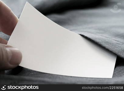 close up of hand picking blank business card from gray suit pocket background