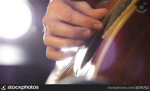 Close up of hand playing acoustic guitar. Hand picking chords on classical wooden guitar in studio during track record.