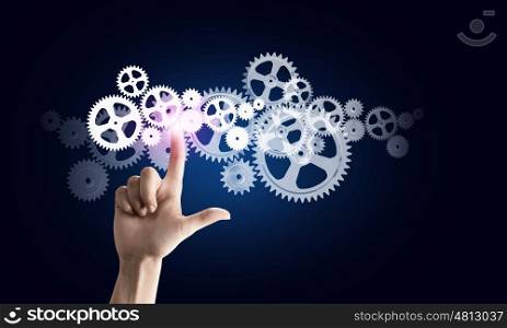 Close up of hand touching icon of gears on media screen. Working mechanism