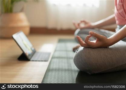 Close up of hand woman doing lotus yoga exercises on yoga mat with Training online on the tablet at home morning, Concept of relaxation and meditation