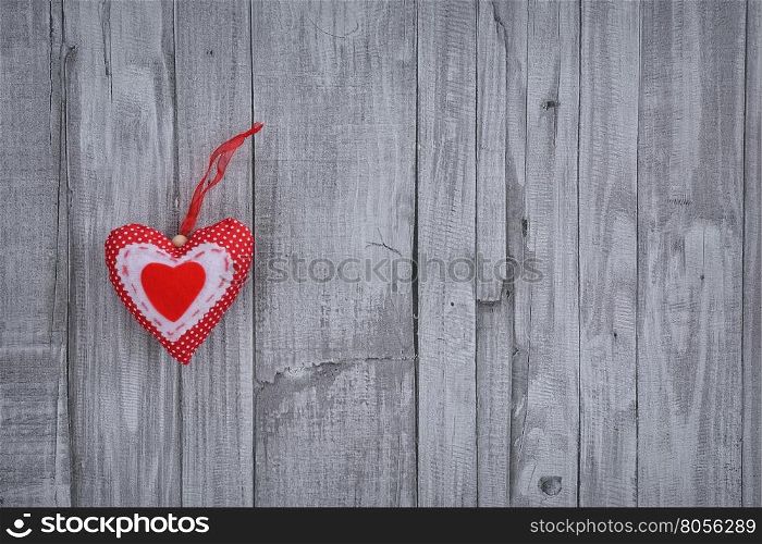 Close-up of handmade red valentine heart pinned on wooden background. Copyspace.