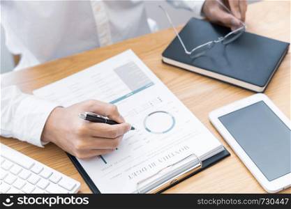 Close-up of hands Businessman reading and writing with pen signing contract over document for Completing Application Form at work in office