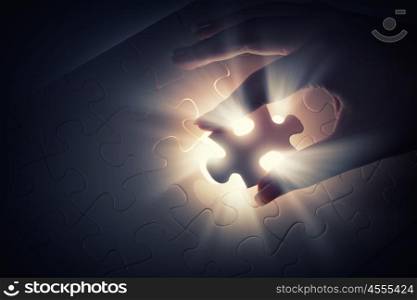 Close up of hands connecting puzzle element and making jigsaw complete. Jigsaw game