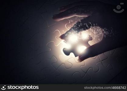 Close up of hands connecting puzzle element and making jigsaw complete. Jigsaw game