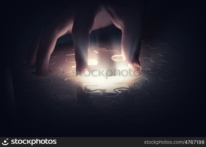 Close up of hands connecting puzzle element and making jigsaw complete. Jigsaw game