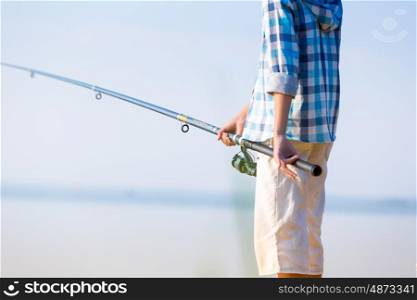 Close-up of hands of a boy with a fishing rod. Close-up of hands of a boy with a fishing rod that is fishing on the pier