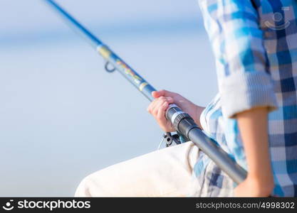 Close-up of hands of a boy with a fishing rod. Close-up of hands of a boy with a fishing rod that is fishing on the pier