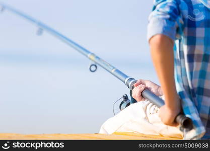 Close-up of hands of a boy with a fishing rod. Close-up of hands of a boy with a fishing rod that is fishing on the pier