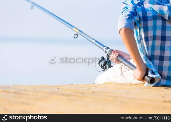 Close-up of hands of a boy with a fishing rod. Close-up of hands of a boy with a fishing rod that is fishing on the pier