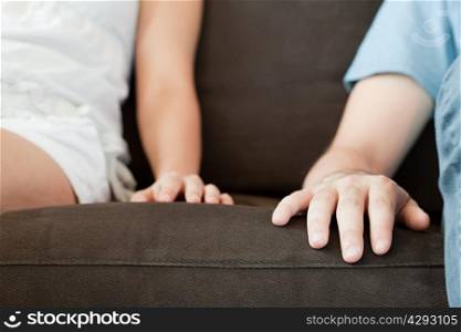 Close up of hands of couple on sofa