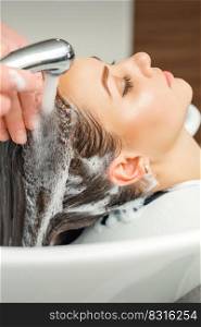 Close up of hands of hairdresser washing hair of woman in sink at beauty salon. Hands of hairdresser washing hair of woman