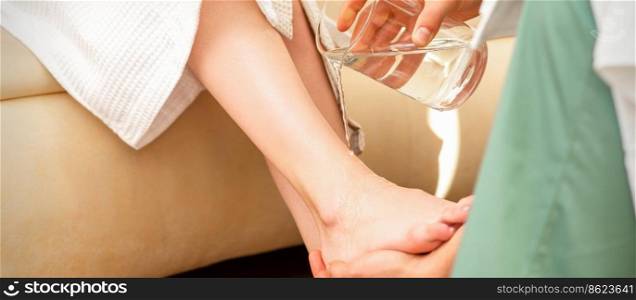 Close up of hands of male therapist washing legs of a young woman in beauty spa salon. Hands of therapist washing legs