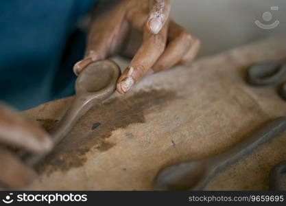 Close up of hands shaping a small clay spoon . Close up of hands shaping ceramic