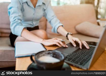 Close-up of hands typing of freelance business female casual working with laptop computer and Taking written Notes to on notebook,warm milk cup in coffee shop like,Distance job communication concept