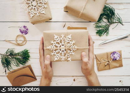 Close up of hands woman present gift box on wooden table with xmas decoration.