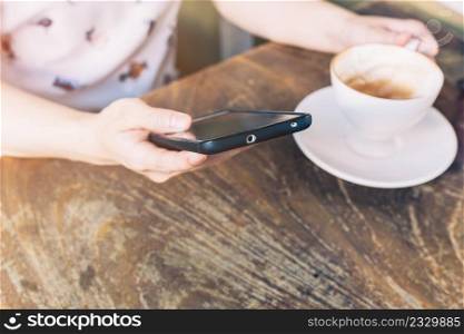 Close up of hands woman using phone in coffee shop with depth of field