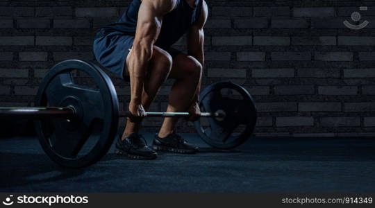 Close up of handsome bodybuilder guy prepare to do exercises with barbell in a gym.bodybuilder?s hand is lifting the barbell and exercising in the gym.low key