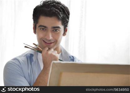 Close-up of handsome young artist painting in art studio