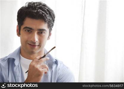 Close-up of handsome young man holding paintbrush in art studio