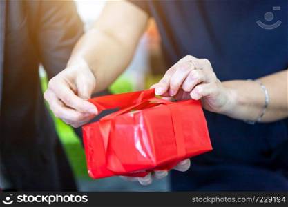 Close up of Happy couple holding wrapping a gift wrap ribbon a present in Christmas and New Year&rsquo;s Eve party Christmas tree background After finishing business work