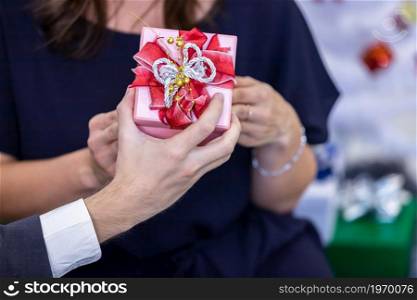 Close up of Happy couple of wrist in a business suit holding exchanging gift box and Give a present in Christmas and New Year&rsquo;s Eve party Christmas tree After finishing business work