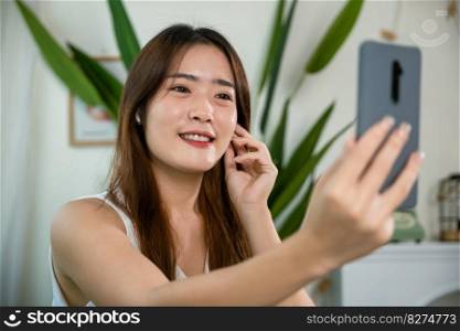 Close up of Happy female touching earbuds to control next listen song on mobile phone in living room at home, Lifestyle woman wearing wireless earphones listening to favorite song on her smartphone