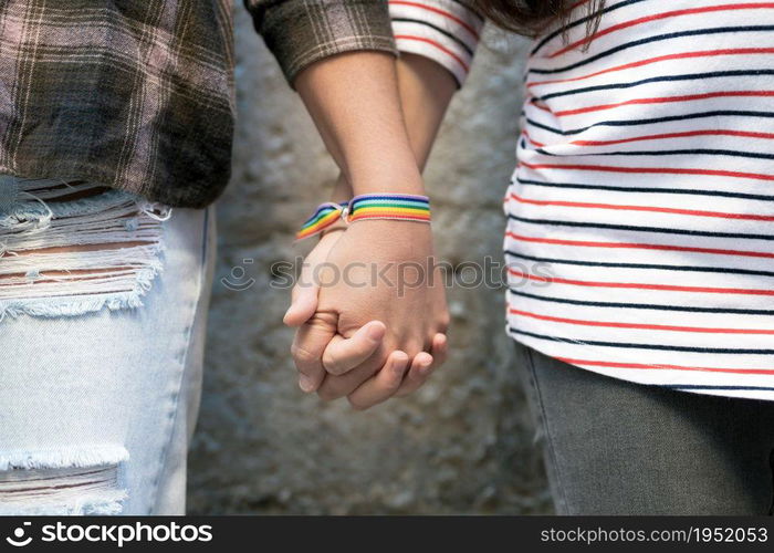 Close up of happy lesbian couple holding hands wearing rainbow flag wristband, LGBT love concept. High quality FullHD footage. Close up of happy lesbian couple holding hands wearing rainbow flag wristband, LGBT love concept.