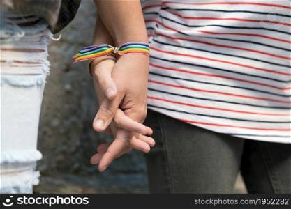 Close up of happy lesbian couple holding hands wearing rainbow flag wristband, LGBT love concept. High quality FullHD footage. Close up of happy lesbian couple holding hands wearing rainbow flag wristband, LGBT love concept.