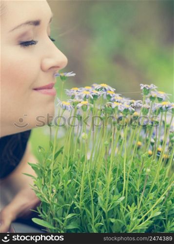 Close up of happy woman smelling wild flowers. Female being with nature. Woman smelling flowers