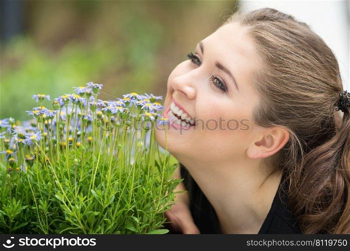 Close up of happy woman smelling wild flowers. Female being with nature. Woman smelling flowers