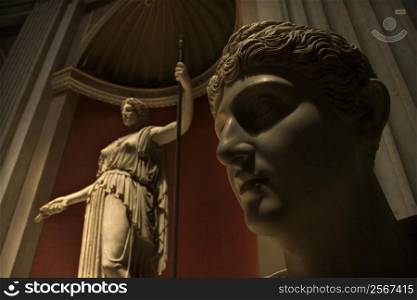 Close-up of head of sculpture with figure sculpture in background in the Vatican Museum, Rome, Italy.