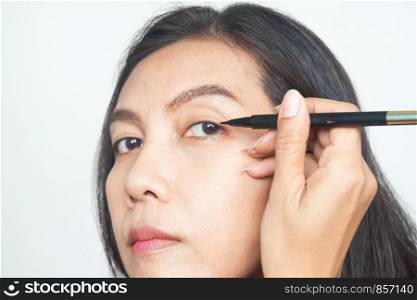 Close up of healthy 40s of Asian woman getting make-up. Applying eye liner on her eyes. Healthy and younger. Health and Beauty concept