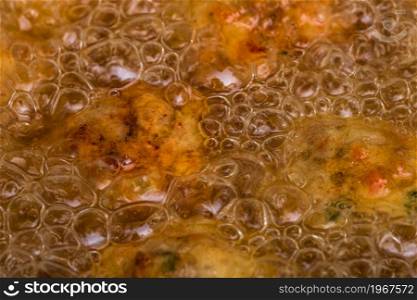 Close-up of hot boiling oil in skillet. Preparing homemade meatballs.