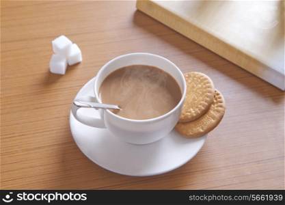 Close-up of hot tea, biscuits and sugar cubes on table