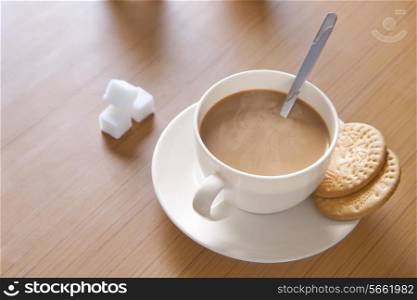 Close-up of hot tea, sugar cubes and biscuits on table