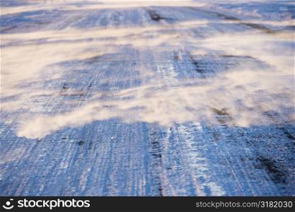 Close up of ice covered road with tire marks.