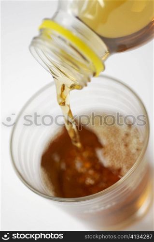 Close-up of ice tea pouring into a glass from a bottle
